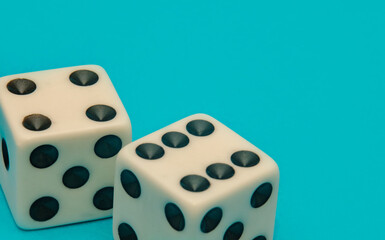 A detailed macro crop shot of a pair of old and real gaming dice resting on a vibrant teal background. Dices offering concepts of chance and risk. Great for gambling themes.