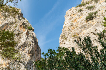 Low-Angle View of a Narrow Rocky Canyon with Sheer Limestone Walls Framing a Bright Blue Sky