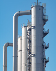 Fototapeta premium Industrial metal towers with pipes under bright blue sky during daytime