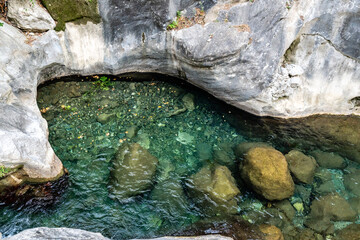 Top-Down View of a Natural Emerald Pool in a Limestone Riverbed with Smooth Boulders and Clear Water
