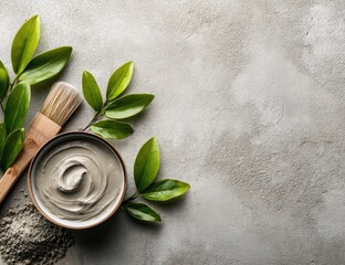 Spa clay mask and brush with green leaves on a textured background.