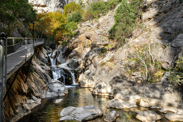 Wide View of a Scenic Canyon River with Small Cascading Waterfalls and a Modern Elevated Pedestrian Walkway