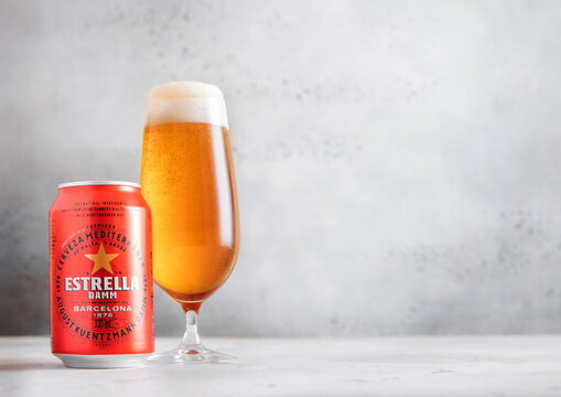 LONDON,UK - NOVEMBER 29, 2025: Glass of Estrella Damm beer with aluminium tin on light table background.