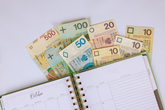 Polish zloty different denominations banknotes are arranged around planner page for October