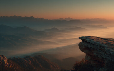 Grandeur of Nature: Extreme Wide Shot of Mountain Cliff Overlooking Foggy Valley at Sunrise
