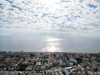 Stunning High-Angle Aerial View of a Coastal City and its Beachfront Bordering the Sparkling Mediterranean Sea on a Sunny Day