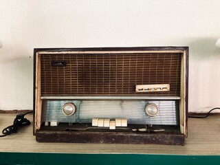 vintage wooden radio receiver with analog tuning dial on a wooden shelf