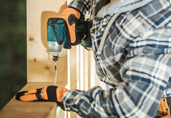 Person Using Power Drill to Fix Wooden Board in Construction Area