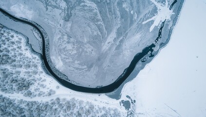 Aerial View of a Frozen River, Adjacent Forest, and Surrounding Snowy Landscape.