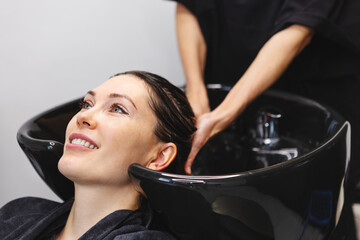 Woman receiving hair wash and massage from hairdresser in salon. Hair care and beauty treatment for client at spa