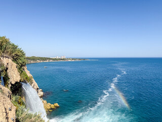 Stunning View of Lower Duden Waterfall Plunging Directly into the Mediterranean Sea with a Small Rainbow and the Antalya Skyline