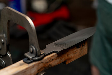 A close-up of a craftsman's hands as he creates a hunting knife.