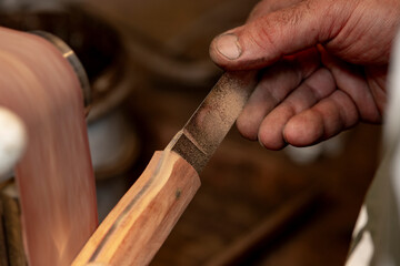 A close-up of a craftsman's hands as he creates a hunting knife.