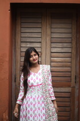 Fototapeta premium Elegant Woman Posing in Front of a Rustic Wooden Shutter
