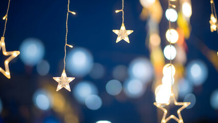 Christmas string lights with stars on blue night abstract bokeh background

