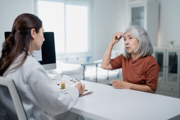 Obraz premium Senior woman discussing headache symptoms with doctor