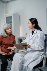 Fototapeta premium Doctor consulting with senior Asian woman about healthcare
