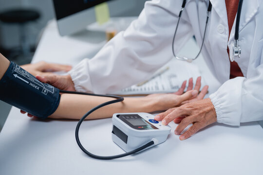 Doctor checking patient blood pressure measuring hypertension