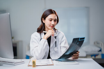 Asian female doctor analyzing x-ray during medical diagnosis