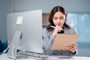 Asian businesswoman analyzing document at office desk