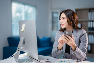 Asian businesswoman multitasking looking at computer and smartphone