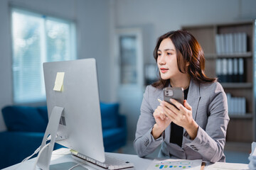 Asian businesswoman multitasking work using smartphone and computer
