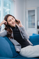 Asian businesswoman talking on phone relaxing on couch