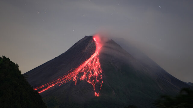 Red glowing volcanic lava descending the steep slopes of Mount Merapi in Indonesia. Powerful natural geological activity illustrating heat, danger, and the force of an active volcano.