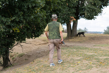 A hunter with a gun in camouflage clothing. A gentleman with a gun, medium shot, unrecognizable.