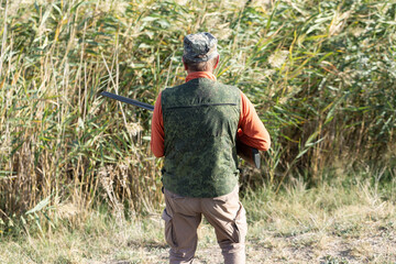 A hunter with a gun in camouflage clothing. A gentleman with a gun, medium shot, unrecognizable.