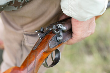 Close-up of a hunter's hand with a gun. Medium shot of a hunter with a weapon.
