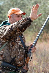 A hunter with a gun in camouflage clothing. A senior man with a gun, medium shot, searching for game.