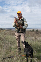 A hunter holds a pheasant in his hands. A successful hunt, a trophy game.