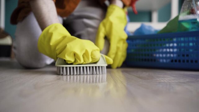 Close up of scrubbing the floor with a plastic brush for deep cleaning.