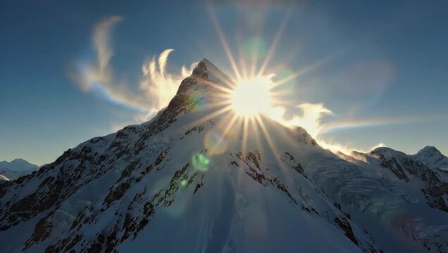 Snowy Mountain Peak with Sunburst and Wispy Clouds.