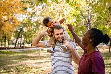 Naklejka premium Family enjoying a playful autumn day in the park with laughter