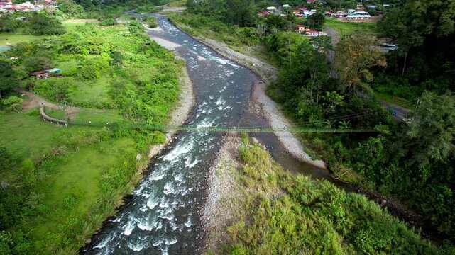 Aerial view of people crossing a bridge in the middle of nature
