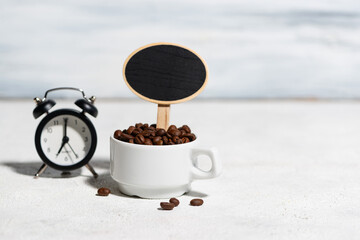 a cup with coffee beans a sign in it, and an alarm clock