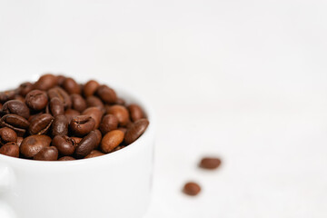 white cup with coffee beans and a white background, close-up