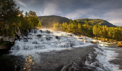 view of the broad Vallestadfossen Waterfall in southwestern Norway in golden morning light
