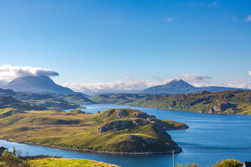 Hidden Scotland. NC500 route. Scenic mountain lake landscape with islands under clear blue sky and rolling green hills