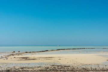 Tranquil beach scene with clear blue sky, turquoise water and sandy shoreline