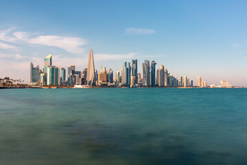Fototapeta premium Panoramic view of West Bay in Doha Skyline Over Calm Sea: Modern Cityscape With Tall Buildings And Blue Sky
