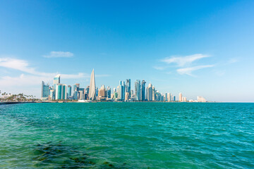 Panoramic view of West Bay in Doha Skyline Over Calm Sea: Modern Cityscape With Tall Buildings And Blue Sky