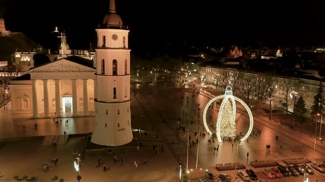 Night aerial view of Vilnius Cathedral Square with the 2024 Christmas tree installation and surrounding Old Town rooftops. A festive cityscape blending history, winter charm, and quiet celebration.