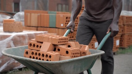 A builder carrying bricks in a wheelbarrow, with a focus on construction and hard work