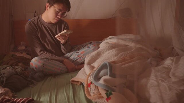 A heartbroken 30-year-old man, living alone in his apartment bedroom in Shenzhen, Guangdong Province, China, sings loudly to relieve his emotions.