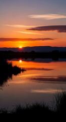 Obraz premium A vibrant sunset over a calm body of water, creating a stunning reflection. Dark silhouettes of land & foliage below