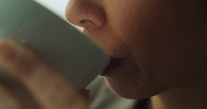 Woman pauses to enjoy steaming cup of coffee with gentle morning light