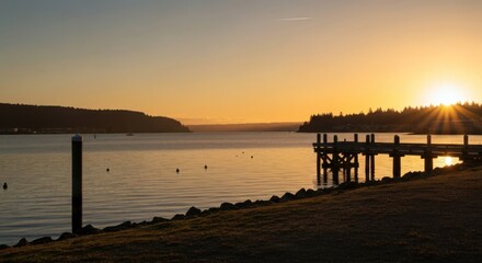 Golden sunset over a calm lake, pier silhouette, and distant hills